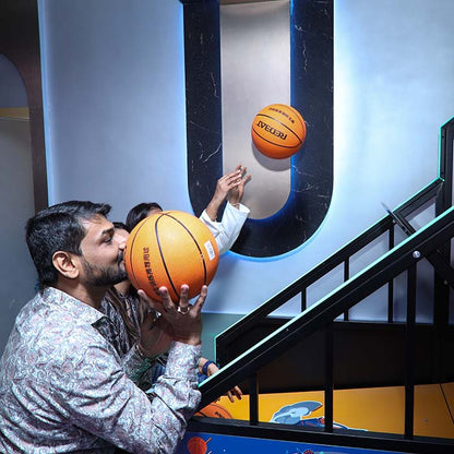 A man holds a basketball to his face while another person throws a basketball in a game.