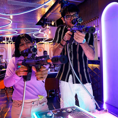 Two young adults play a laser tag game in a dimly lit, neon-lit arcade.