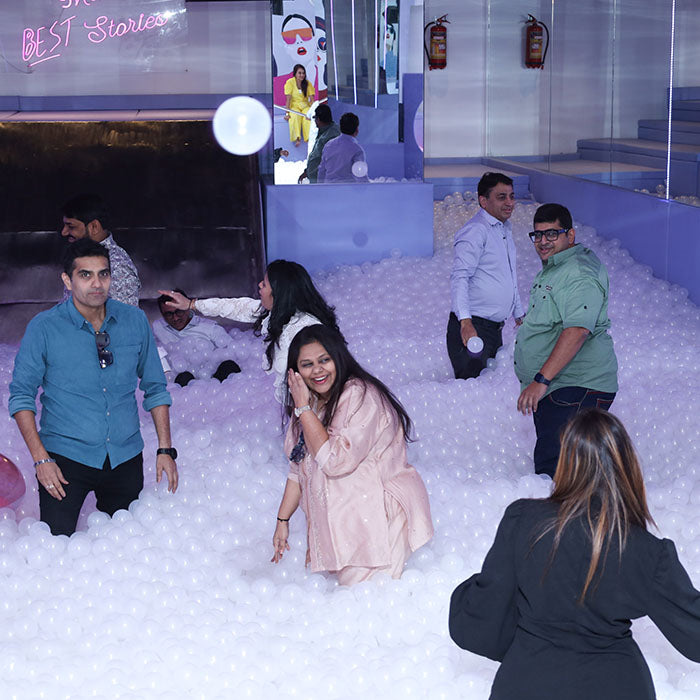 Adults play in a ball pit at an indoor venue.