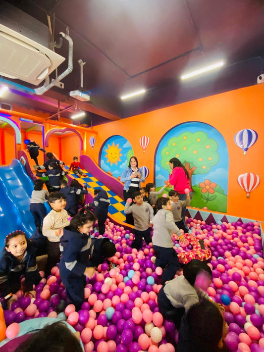 Children playing joyfully in a colorful ball pit with slides and bright wall murals at Arno's Den indoor play area