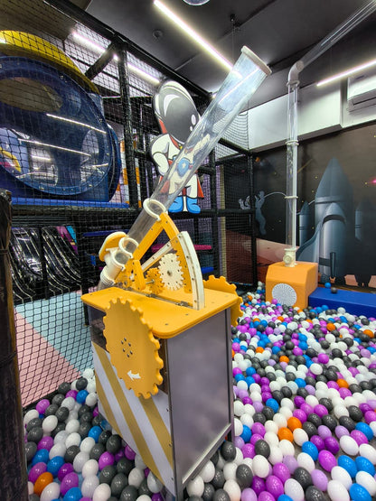 A children's ball pit with a space-themed playground structure and a clear tube.