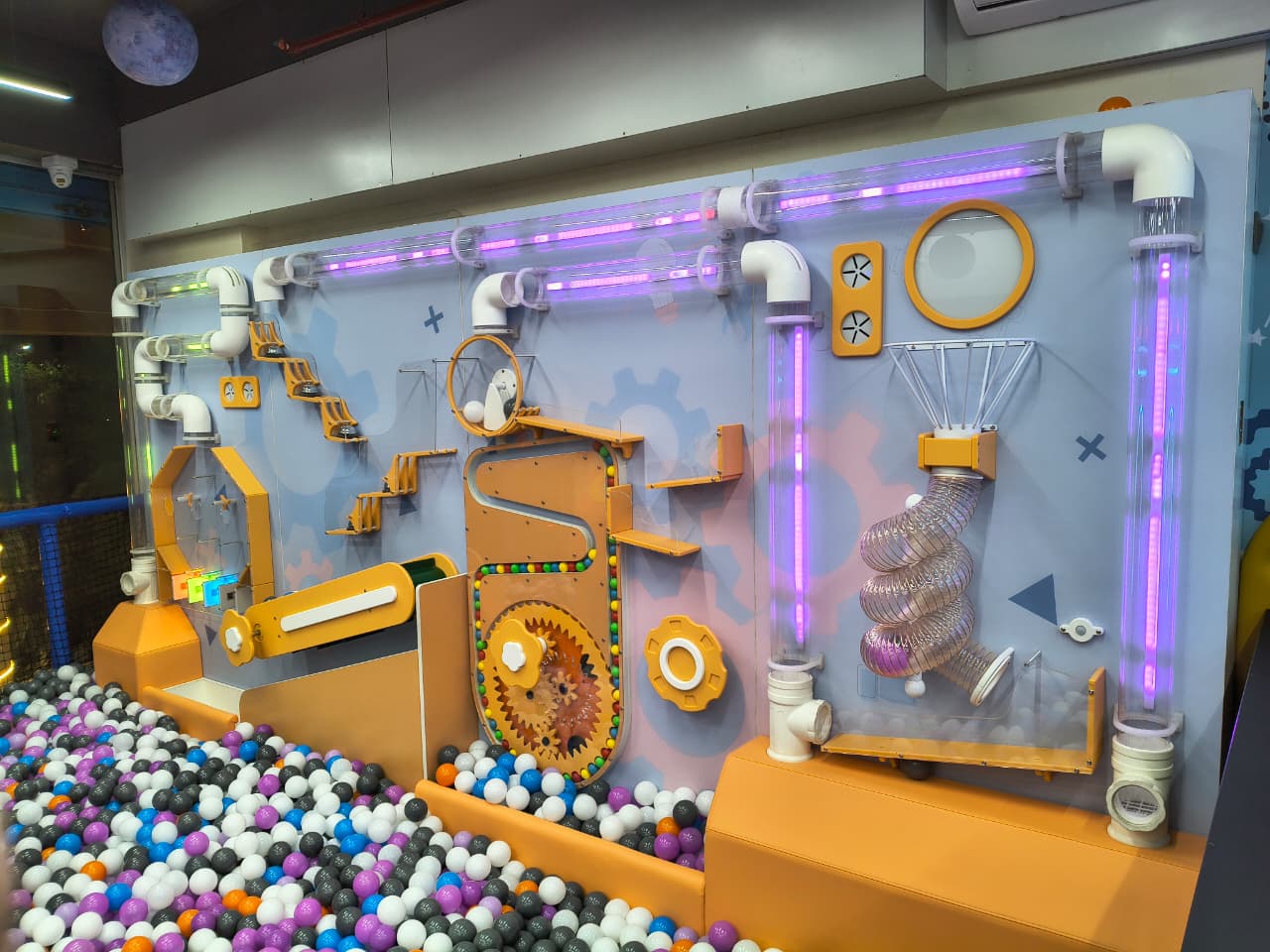 A colorful ball pit with a complex ball-run activity wall for children.