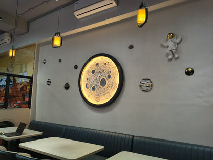 A restaurant with space-themed decor, featuring a moon clock, astronaut figures, and planets.