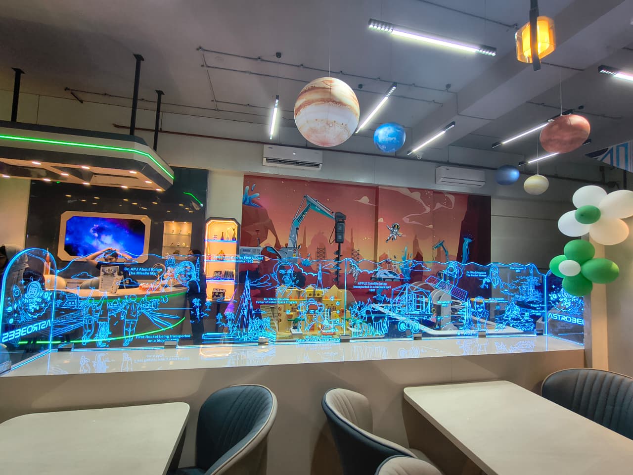 A display of space-themed exhibits with planets hanging from the ceiling and a mural in the background.