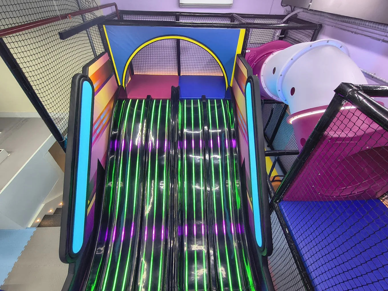 A colorful indoor playground slide with neon lights, designed for children.