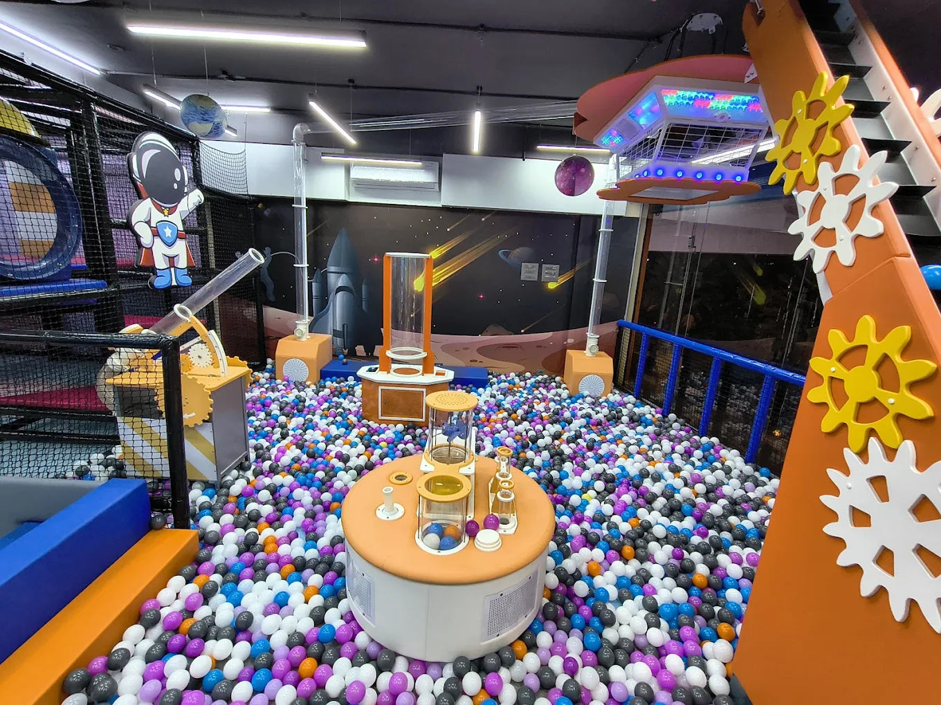 A ball pit with colorful balls and space-themed decorations, likely for children.