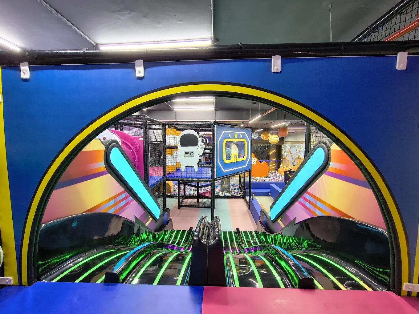 A colorful indoor playground with slides and an astronaut decoration.