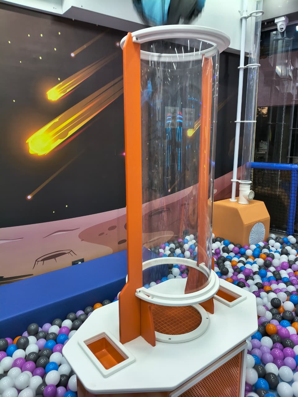 A children's ball pit with a space-themed mural and a clear tube attraction.