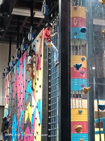 Two children climb a colorful indoor rock-climbing wall.