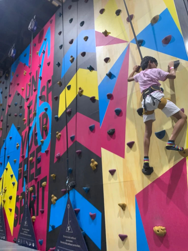 A child climbs a colorful indoor rock wall.