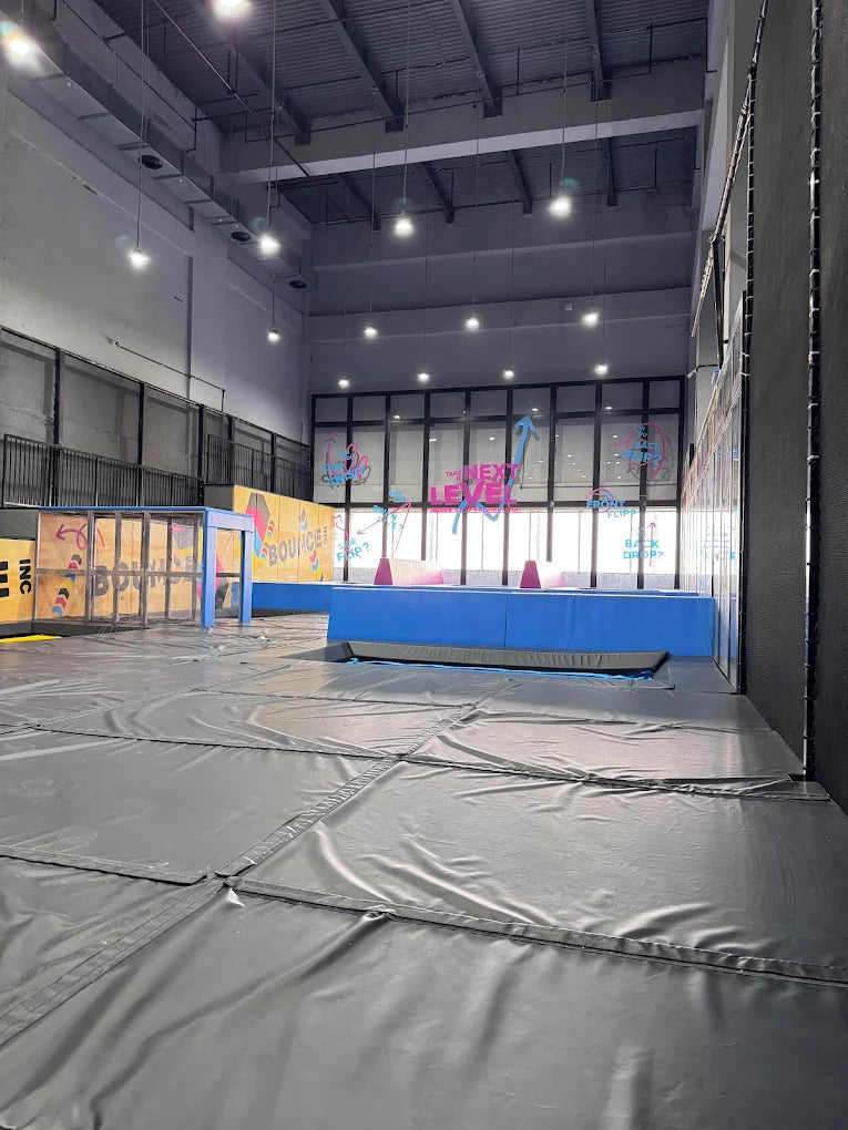 An indoor trampoline park with padded floors and colorful walls.