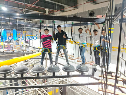 Young people on a ropes course, balancing on pods and holding onto safety lines.