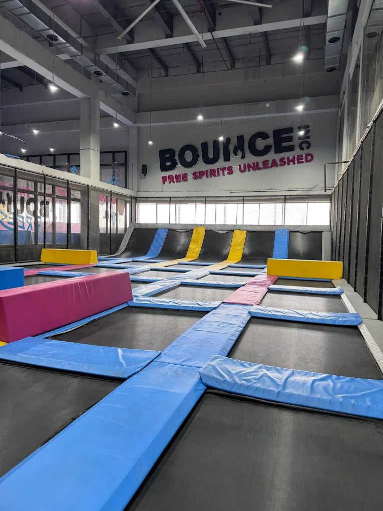 An indoor trampoline park with many trampolines and colorful padding.