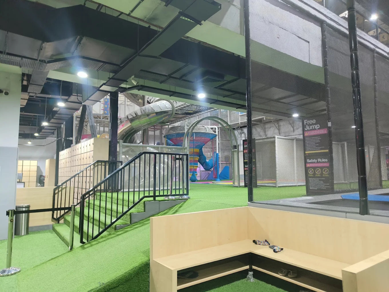 Indoor trampoline park with slides and a seating area.