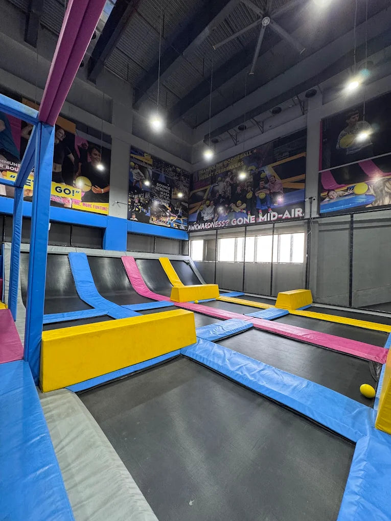 An indoor trampoline park with multiple trampolines and colorful padding.