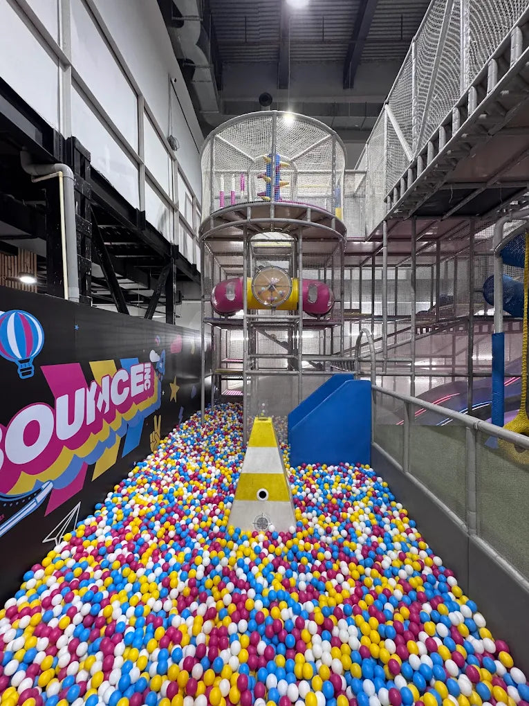 A ball pit filled with colorful balls, leading to a multi-level play structure for children.