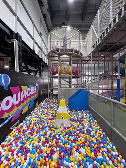A ball pit filled with colorful balls, leading to a multi-level play structure for children.