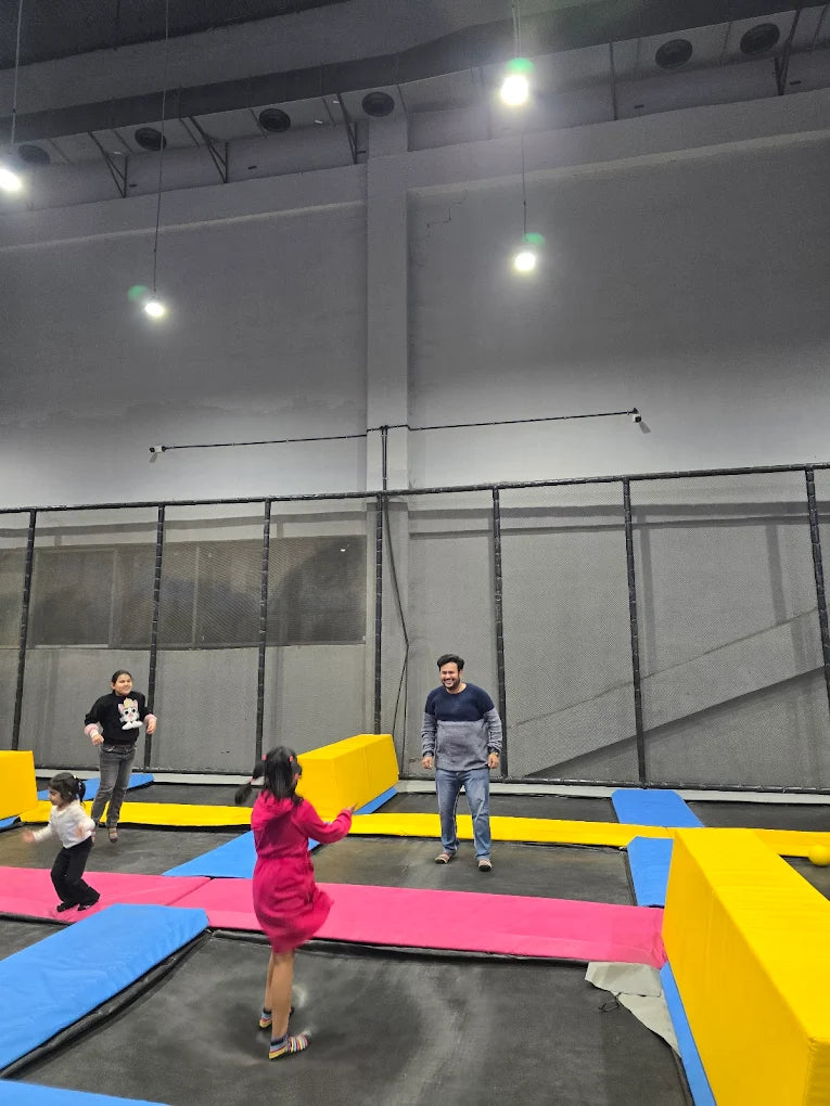 People of various ages enjoy jumping on trampolines in an indoor park.