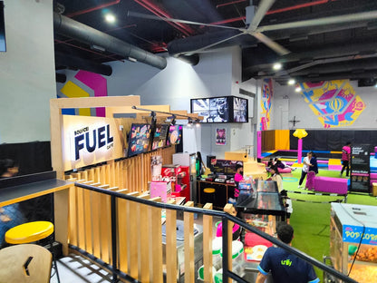 An indoor trampoline park with a cafe, featuring young people jumping and playing.
