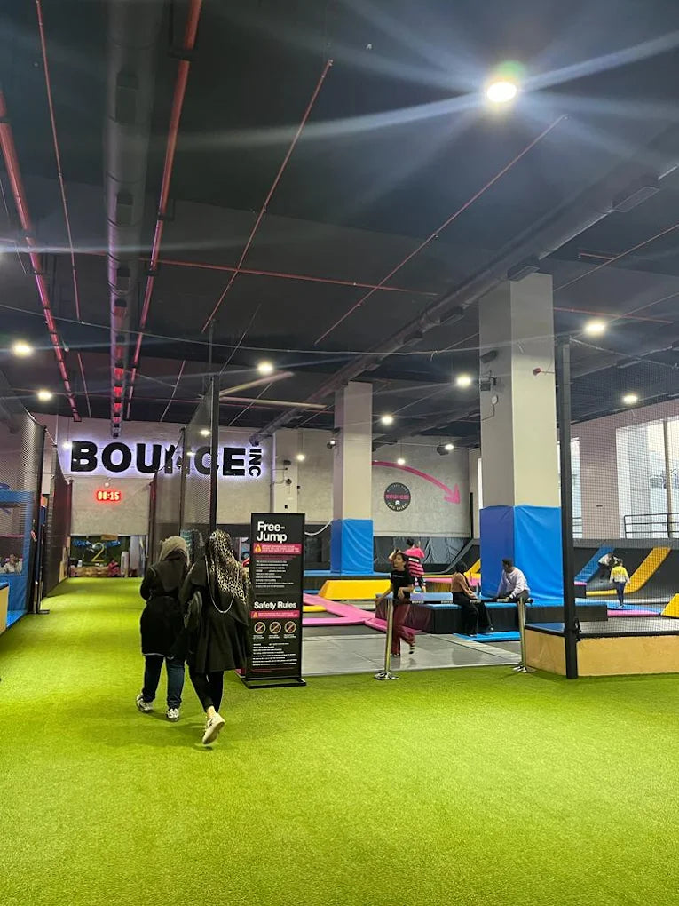People at a trampoline park with a "Bounce Inc." sign and safety rules displayed.