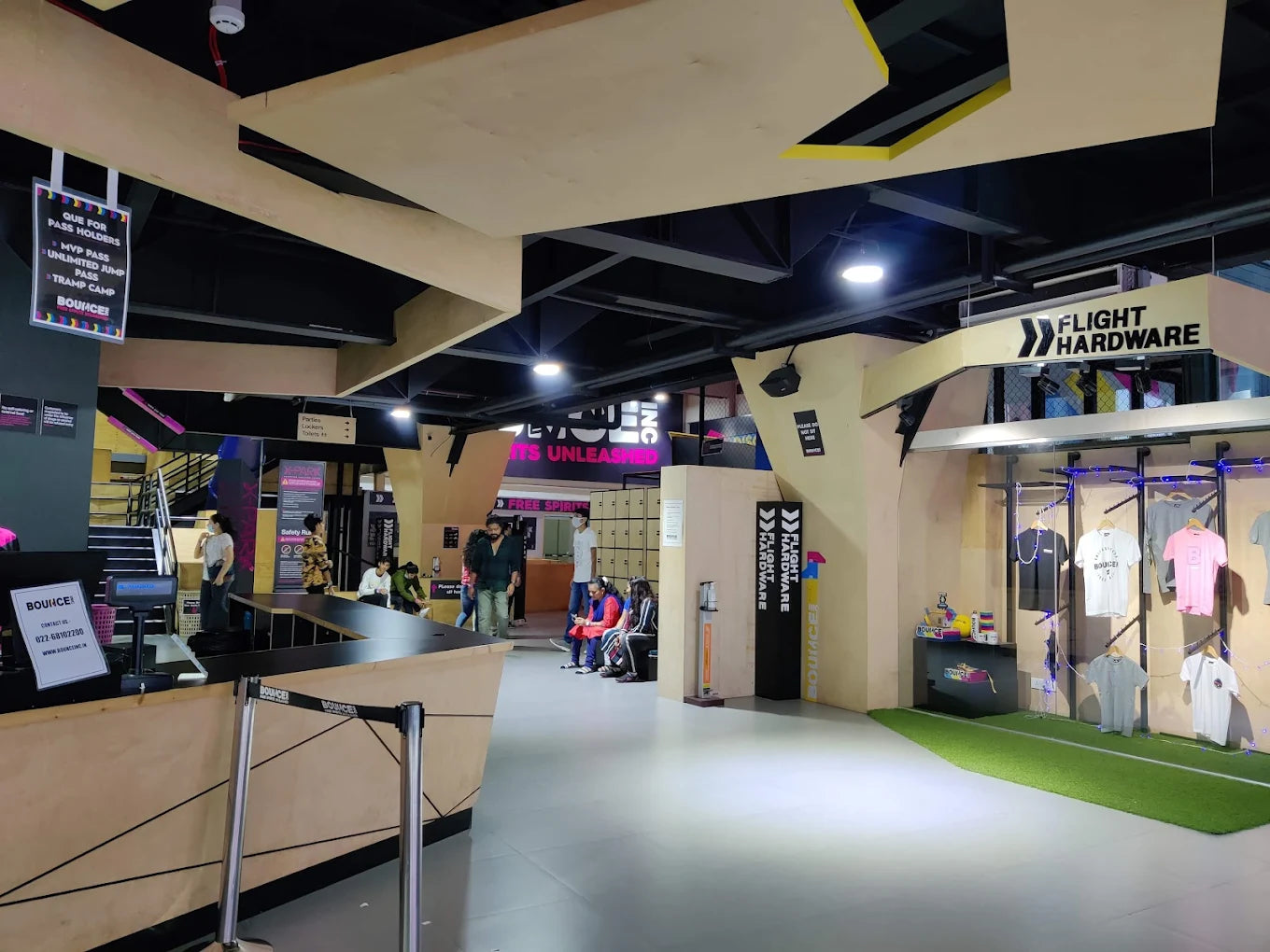 An indoor trampoline park with people at the reception and a merchandise display.