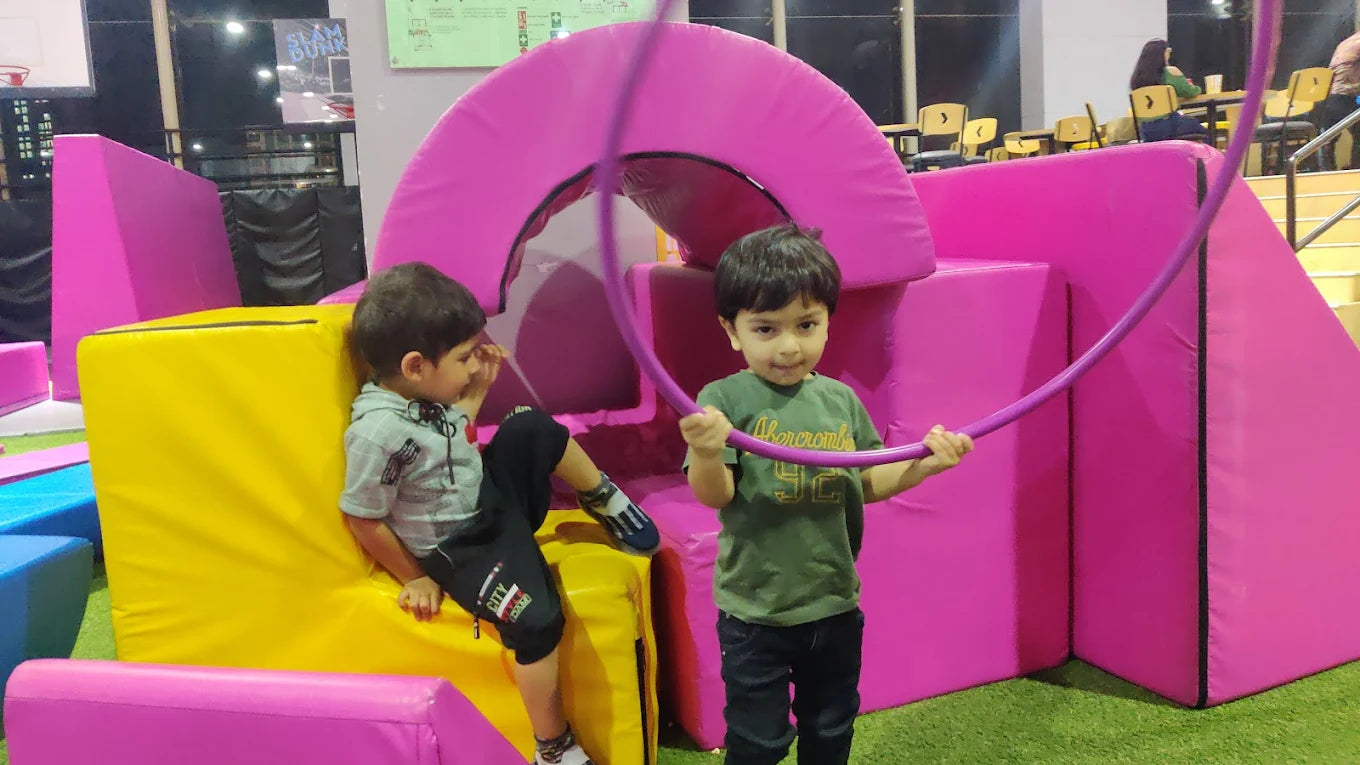 Two young boys play with a hoop in a colorful indoor play area.