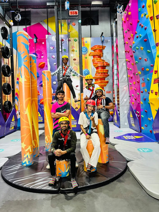 Young adults in climbing gear pose in front of colorful climbing walls.