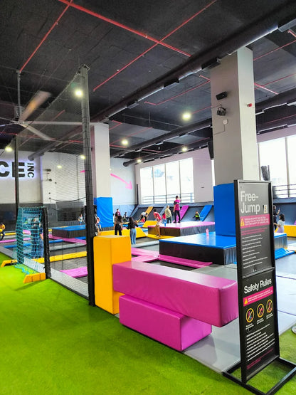 An indoor trampoline park with people of various ages jumping and playing on trampolines.