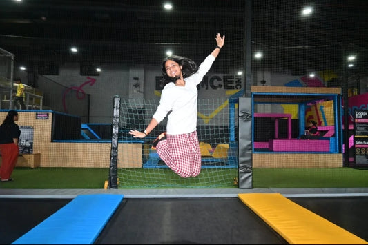 A young person jumps high in the air at an indoor trampoline park.
