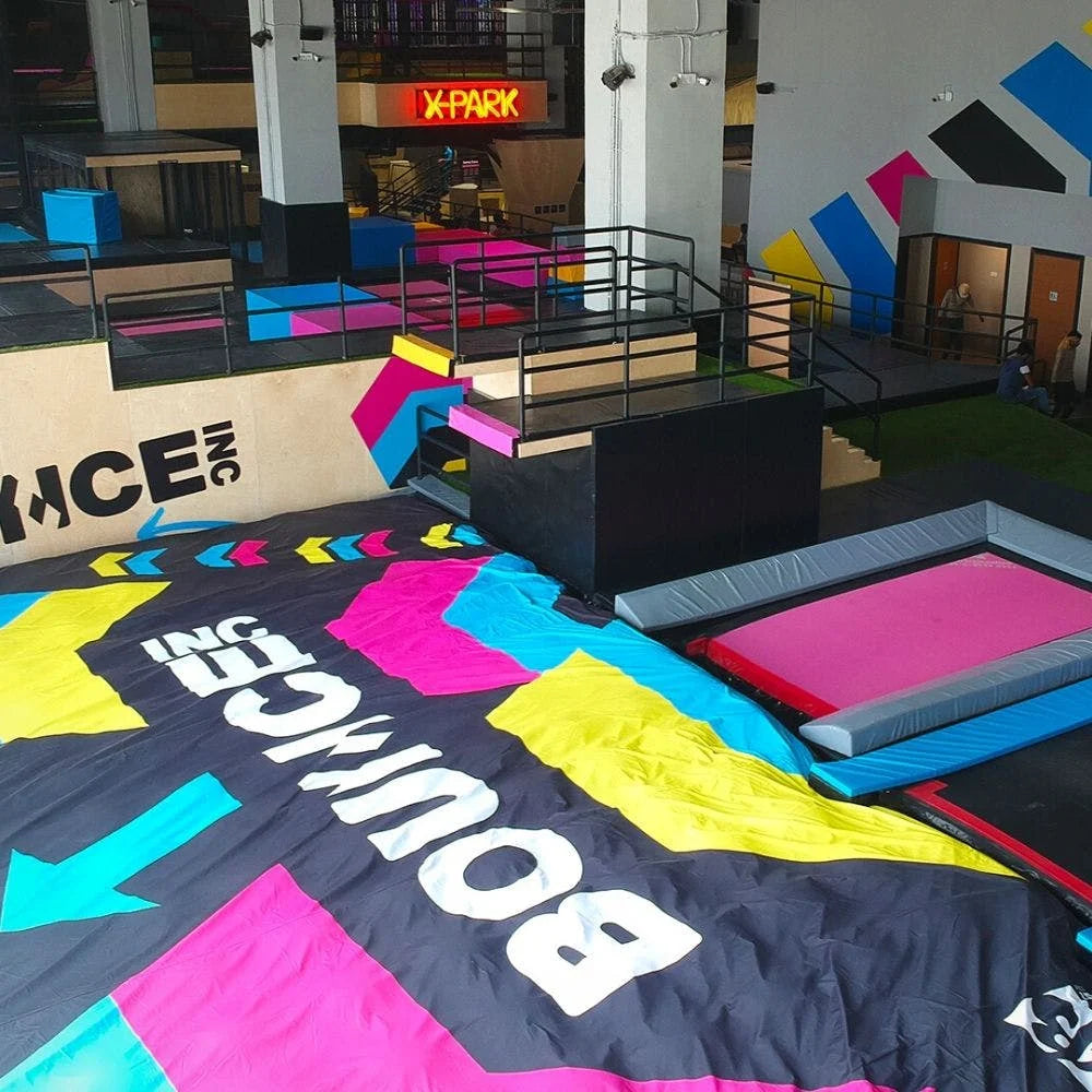 An indoor trampoline park with colorful mats and obstacles, featuring young people enjoying the activities.