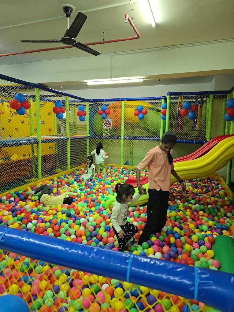 Children play in a colorful ball pit with a slide.