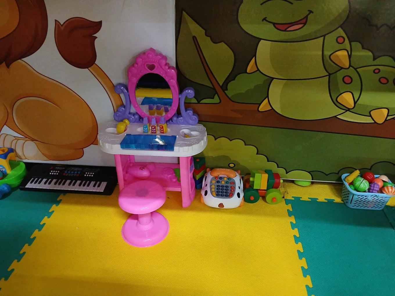 A child's play area with a toy vanity, keyboard, and pretend food.