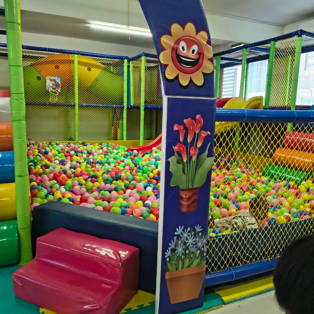 A colorful ball pit in a children's play area with a slide and soft play structures.