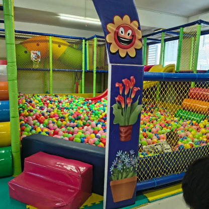 A colorful ball pit in a children's play area with a slide and soft play structures.