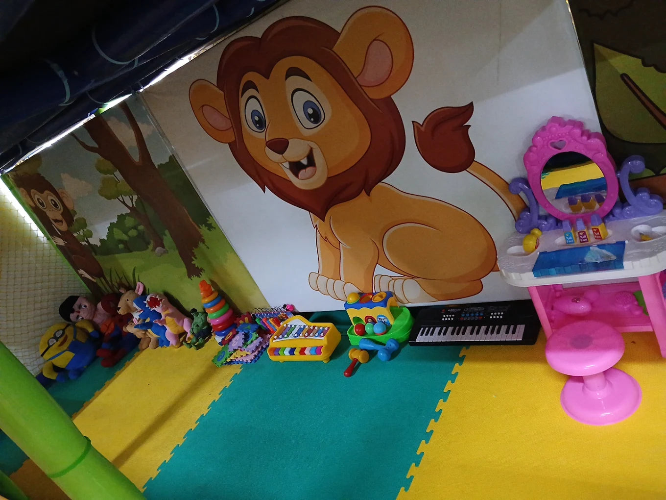 A playroom with toys and a cartoon lion mural. A toy vanity and keyboard are visible.
