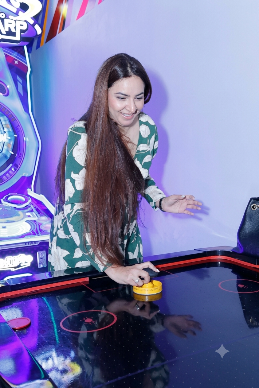 A young woman plays air hockey in an arcade.
