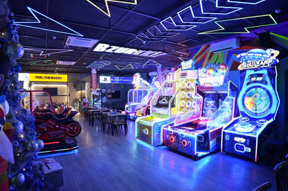 An arcade filled with colorful, neon-lit games and a motorcycle ride, with tables and chairs in the background.