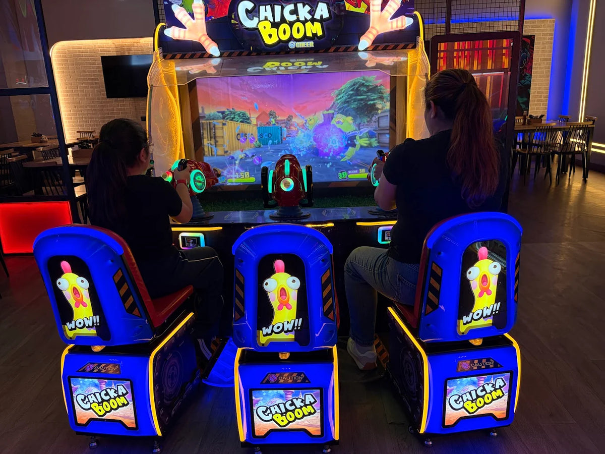Two people play a "Chicka Boom" arcade game in a dimly lit entertainment venue.