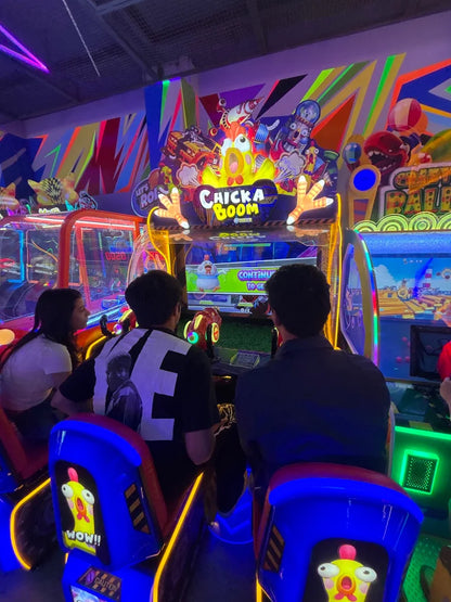 Young adults play an arcade game called "Chicka Boom" in a brightly lit arcade.