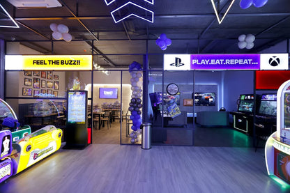An arcade with gaming machines, seating areas, and neon signs.