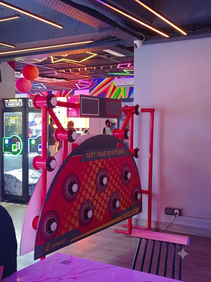 A reaction game with flashing lights and screens in an arcade, with young adults playing.