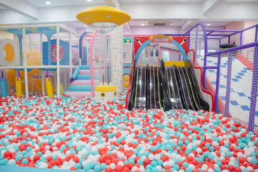 A colorful indoor playground with a ball pit, slides, and climbing structures for children.