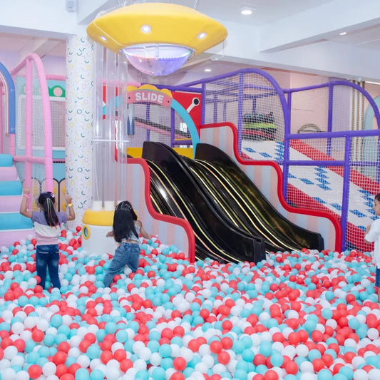 Children play in a ball pit with slides and a UFO-shaped light fixture.