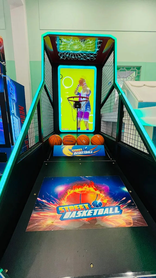 An arcade basketball game with four balls and a screen showing a person playing.