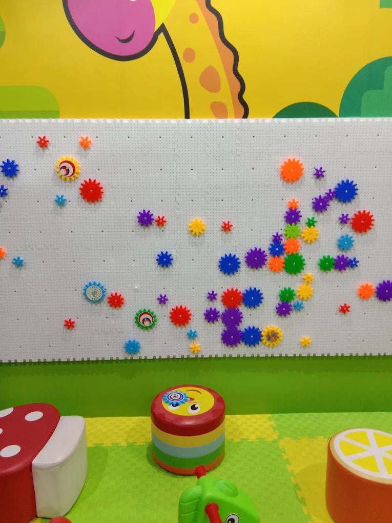 A colorful pegboard wall with gears and toys in a playroom.