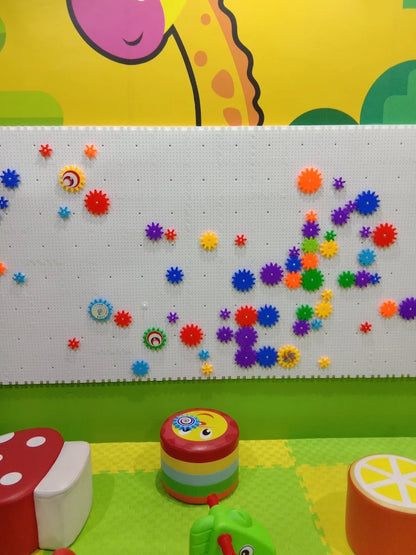 A colorful pegboard wall with gears and toys in a playroom.
