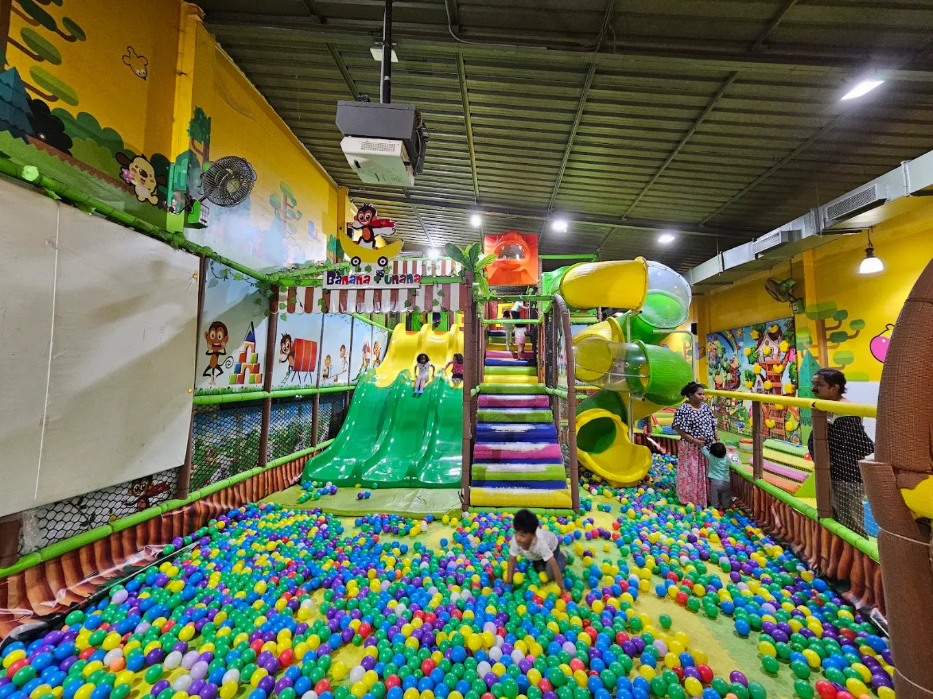 Children play in a colorful ball pit and on a multi-level playground structure.