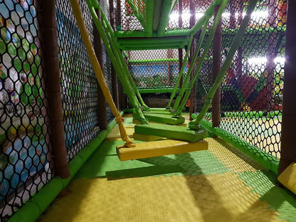 A colorful indoor playground with rope bridges and soft flooring.