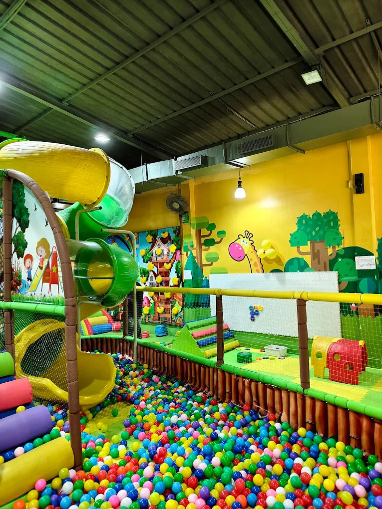 A colorful indoor playground with slides and a ball pit, filled with children playing.