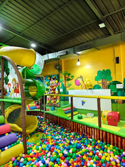 A colorful indoor playground with slides and a ball pit, filled with children playing.